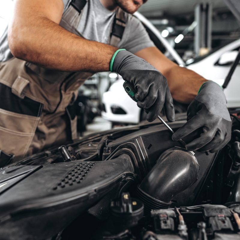 Close up photo of mechanic's hands repairing car engine in car service